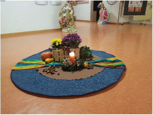 runder blauer Teppich mit brennender Kerze, dekoriert mit Blumen und Kürbis