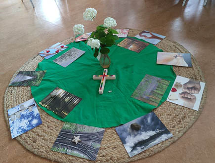 Gestaltete Mitte mit Kreuz, Blumen und Bildern bei der Frühschicht in der Pestalozzischule