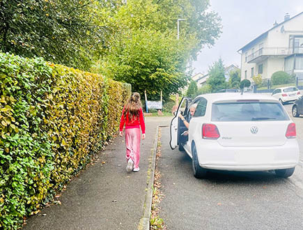Schülerin auf dem Gehweg neben einem Auto im Rahmen des Sicherheitstrainings